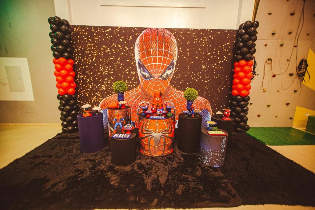 A colorful Spiderman themed birthday party decoration with balloons and figurines.