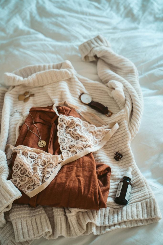 Stylish morning setup with cozy clothes and accessories on a bed.