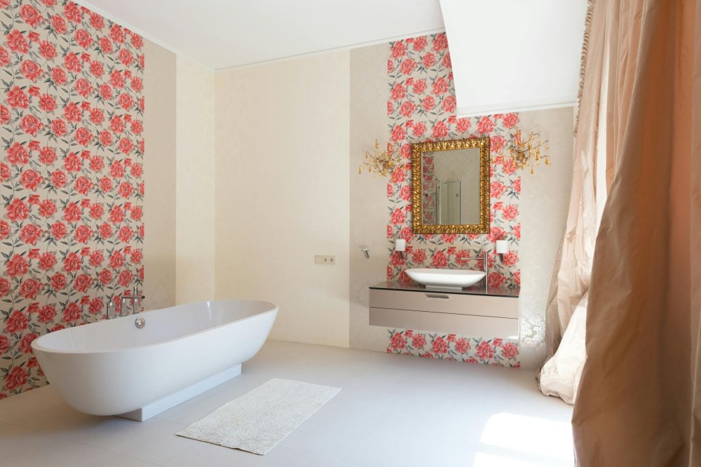 Spacious and elegant bathroom with a freestanding tub, floral wallpaper, and gold accents.