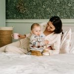 A mother shares a warm moment with her child on a cozy bed with wooden toys.